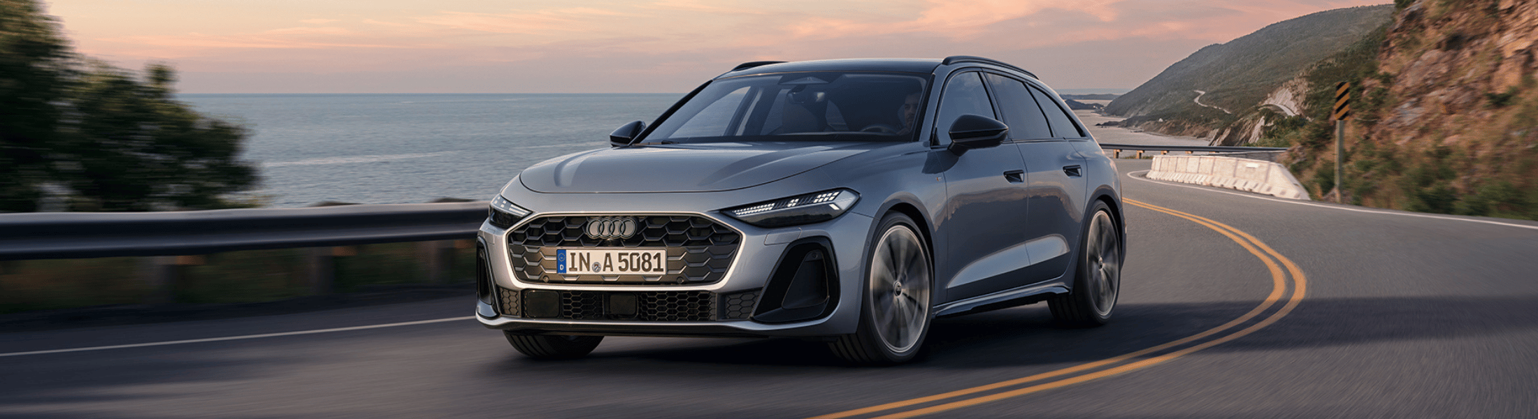 Grauer Audi A5 von schräg vorne fährt auf einer ku