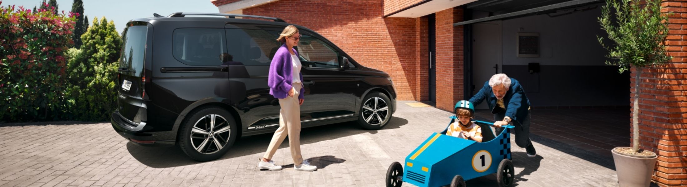 VW Caddy in schwarz vor einer Garage